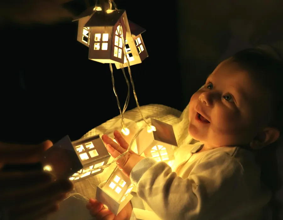 Ett barn håller i en upplyst leksakslampa i ett mörkt rum på kvällen